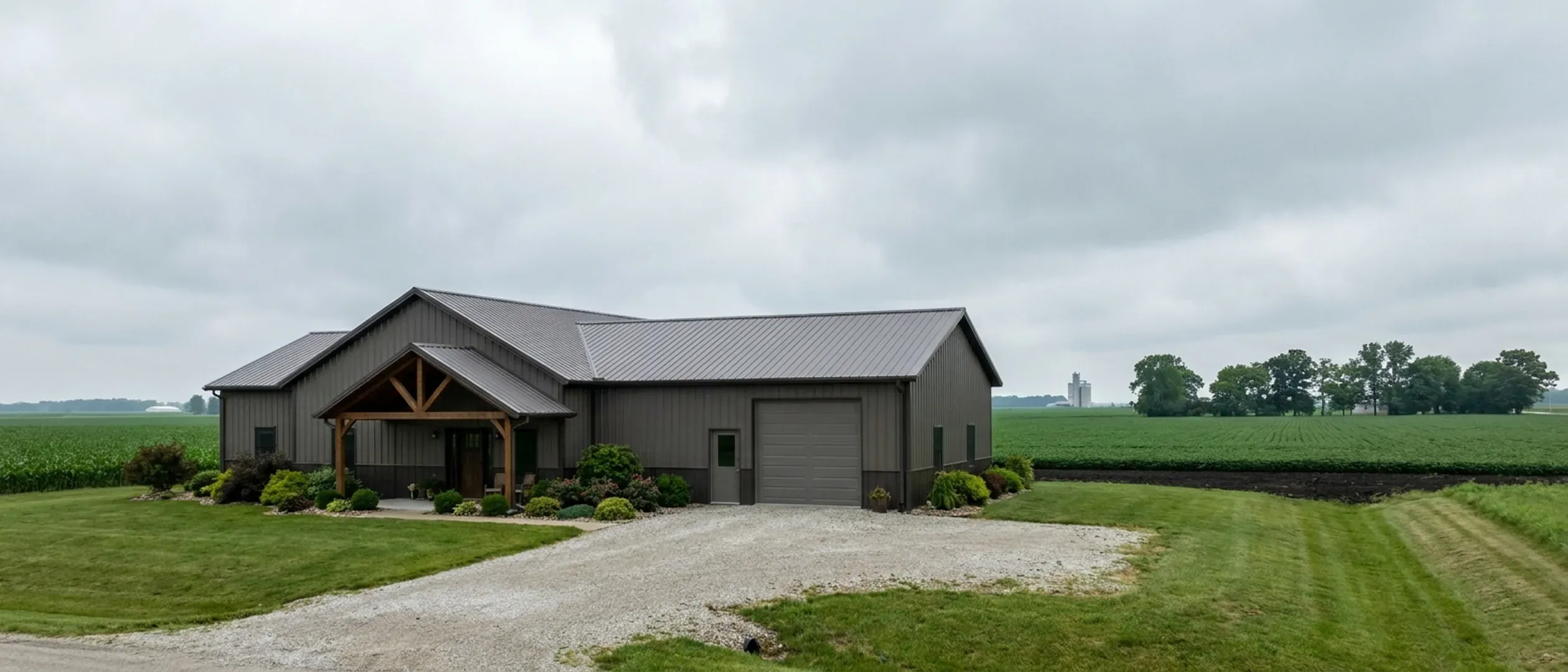 A completed barndominium with a covered entry porch and an attached shop bay, photographed in flat overcast daylight.
